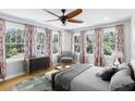 Bright bedroom featuring hardwood floors, many large windows, stylish curtains and ceiling fan at 5632 Indiana Ave, New Port Richey, FL 34652