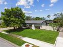 Well-manicured front lawn and garden enhance this single-story home's curb appeal, complemented by a white privacy fence at 6903 Cedar Ridge N Dr, Pinellas Park, FL 33781