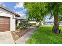 Inviting single-story home with a well-maintained lawn and garden, highlighted by a brown garage door and mature tree at 6903 Cedar Ridge N Dr, Pinellas Park, FL 33781
