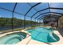 Relaxing screened-in pool and spa with a tranquil lake view, perfect for outdoor entertaining at 10522 Sky Flower Ct, Land O Lakes, FL 34638