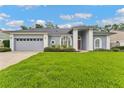 Inviting home with manicured lawn, gray exterior, and a two car garage at 15615 Indian Queen Dr, Odessa, FL 33556