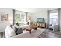 Comfortable living room showcasing gray hardwood floors, large windows, and neutral-toned furniture at 32702 Winterwood Boulevard Blvd, Wesley Chapel, FL 33543