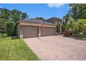 Lovely home featuring a spacious brick driveway leading to a two-car garage and enhanced by lush landscaping at 5101 Hartwell Loop, Land O Lakes, FL 34638