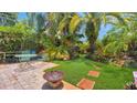 Inviting backyard patio with brick pavers, lush tropical foliage, a fire pit, and outdoor seating at 5835 29Th N Ave, St Petersburg, FL 33710