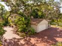 A large brick driveway leads to a two-car garage in this exterior shot with mature trees and landscaping at 8350 40Th N Ave, St Petersburg, FL 33709