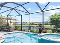 Screened in pool and spa overlooking a tranquil lake view, with patio furniture for outdoor relaxation at 2829 Maple Brook Loop, Lutz, FL 33558