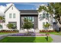 Beautiful two-story home featuring a manicured lawn and garden and a modern gray and white facade at 2902 S Beach Dr, Tampa, FL 33629