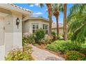 Landscaped walkway leading to the front door with garden and mature palms providing shade and curb appeal at 5009 Sandy Brook Cir, Wimauma, FL 33598