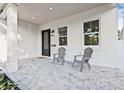 Inviting front porch features stylish gray chairs, a tiled floor, and an elegant black front door with glass accents at 5120 3Rd N Ave, St Petersburg, FL 33710