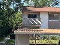 Angle view of a two-story condo featuring a balcony and nearby carport in a sunny, tropical setting at 647 Fairmont Ave # C, Safety Harbor, FL 34695