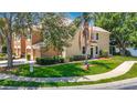 Two story townhome with green lawn and bushes with a palm tree in the front at 8576 Sandy Beach St, Tampa, FL 33634