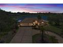 Stunning lakefront home at twilight with lush landscaping, circular driveway, and a spacious three-car garage at 8827 Scout Lake Ct, New Port Richey, FL 34654