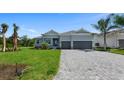 Single-story home with manicured lawn, grey stucco, a 2-car garage, and decorative stone accents at 9295 Rosebud Cir, Port Charlotte, FL 33981