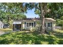Quaint single-story home featuring a cozy facade, large tree, and lush green lawn at 1013 N Bask Dr, Tampa, FL 33603