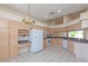 Well-lit kitchen with an abundance of cabinets, a stainless steel refrigerator, and tile flooring at 1126 Haley Ln, Dunedin, FL 34698