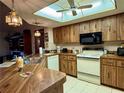Bright kitchen with wood cabinets, a drop in oven, black microwave, and a skylight above at 11430 Nature Trl, Port Richey, FL 34668