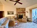 Comfortable living room featuring a stone fireplace, ceiling fan, and sliding glass doors to the patio at 11430 Nature Trl, Port Richey, FL 34668