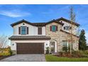 Daytime view of a two-story home featuring stone accents, a tile roof, and a charming arched entryway and a 2-car garage at 13722 Heartwood Way, Parrish, FL 34219