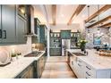 Bright and modern kitchen featuring wood beams, large island, and stainless steel appliances at 13726 Heartwood Way, Parrish, FL 34219