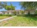Beautiful single-story home featuring arched windows, a tile roof, and manicured landscaping at 3351 Bristol Pl, Tarpon Springs, FL 34688