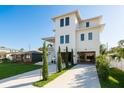 Bright, three-story house with a long driveway and a tidy lawn, showcasing modern architecture at 3752 Arkansas Ne Ave, St Petersburg, FL 33703