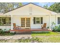 Inviting front porch featuring wood chairs, brick flooring, and a double-door entryway at 4805 E Regnas Ave, Tampa, FL 33617