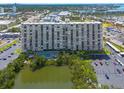 Scenic view of the condo building, pool, lake, and parking area with mature trees surrounding at 7050 Sunset S Dr # 1401, South Pasadena, FL 33707