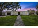 Charming single-story home featuring a well-manicured lawn, a paved walkway, and a welcoming front door at twilight at 75 New Jersey Dr, Dunedin, FL 34698