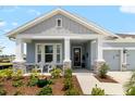 Inviting front porch with stone accents, white columns, rocking chairs, and a beautifully landscaped garden at 8916 Windlass Cv, Parrish, FL 34219