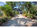 Inviting home featuring lush landscaping, a covered porch, and an expansive driveway leading to the entrance at 1304 Withlacoochee St, Safety Harbor, FL 34695