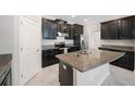 Modern kitchen with stainless steel appliances, granite countertops, a kitchen island, and tile flooring at 13213 Haystack Ct, Riverview, FL 33579