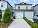 Street view of a two-story townhome with a white garage door and blue siding at 2874 Deer Pine Trl, Land O Lakes, FL 34638