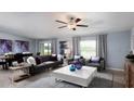 Spacious living room with a plush sofa, ceiling fan, modern decor, and ample natural light streaming through the windows at 4015 86Th E St, Palmetto, FL 34221