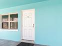 Close-up of a white front door of a turquoise home with a window, creating an inviting curb appeal at 410 73Rd Ave, St Pete Beach, FL 33706