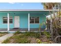 A turquoise home exterior, featuring a covered porch with white support columns and the front door with number 2 at 410 73Rd Ave, St Pete Beach, FL 33706