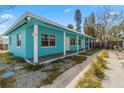 Side view of a turquoise home featuring a long covered porch, white support columns, and lush greenery at 410 73Rd Ave, St Pete Beach, FL 33706