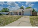 Inviting single-story home with a covered front porch, adjacent to a driveway leading to an attached garage at 4150 Woodsville Dr, New Port Richey, FL 34652