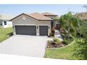 Beautiful home exterior with a tile roof, paver driveway, two car garage, and professional landscaping at 4888 Sevilla Shores Dr, Wimauma, FL 33598