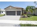 Beautiful home exterior with a tile roof, paver driveway, two car garage, and professional landscaping at 4888 Sevilla Shores Dr, Wimauma, FL 33598