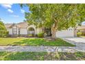 Inviting one-story home with lush front yard, large shade tree, and charming architectural details at 5434 Wellfield Rd, New Port Richey, FL 34655