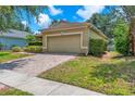 A tan home with a brick driveway leading to a two car garage at 11808 Holly Crest Ln, Riverview, FL 33569