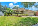 Well-maintained single-story home with green lawn, manicured hedges, and brick paver driveway at 11808 Holly Crest Ln, Riverview, FL 33569