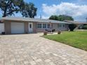 Single-story home with a paver driveway, attached garage, and manicured front lawn at 13725 Bermuda Dr, Seminole, FL 33776