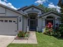 Beautiful one-story home showcasing a well-manicured lawn and colorful landscaping along the front walkway at 18003 Arbor Crest Dr, Tampa, FL 33647
