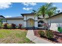 Inviting front exterior with a stone walkway, blooming plants, and a vibrant yellow front door at 1801 Sagebrush Rd, Plant City, FL 33566