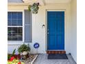 Inviting blue front door framed by manicured landscaping and a charming hanging plant at 1809 Elmwood Dr, Oldsmar, FL 34677