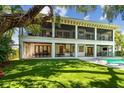 Expansive backyard featuring a covered patio, an outdoor kitchen, dining area, and lush landscaping surrounding a sparkling pool at 4313 W Beachway Dr, Tampa, FL 33609