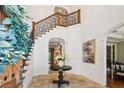Grand foyer with elegant staircase, detailed iron railings, arched doorways and travertine tile flooring at 4313 W Beachway Dr, Tampa, FL 33609