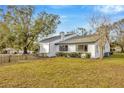 A view of the backyard features well-maintained landscaping and a charming white house with black window trim at 5526 Southernview Dr, Zephyrhills, FL 33541