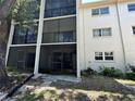 Exterior view of the condominium building featuring screened balconies, windows, and mature plantings at 861 Maple Ct # 104, Dunedin, FL 34698